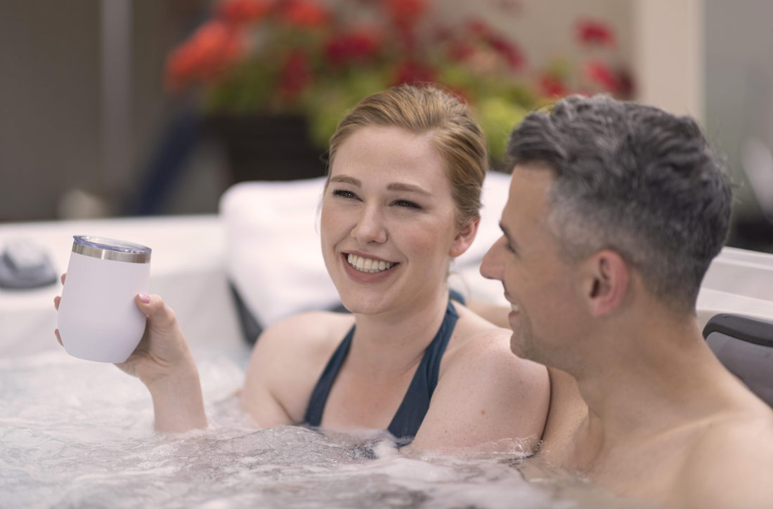 Woman with a cup in her hand in a hot tub next to a man