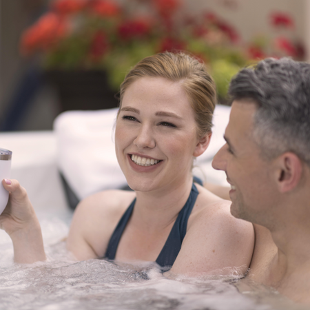 Woman with a cup in her hand in a hot tub next to a man